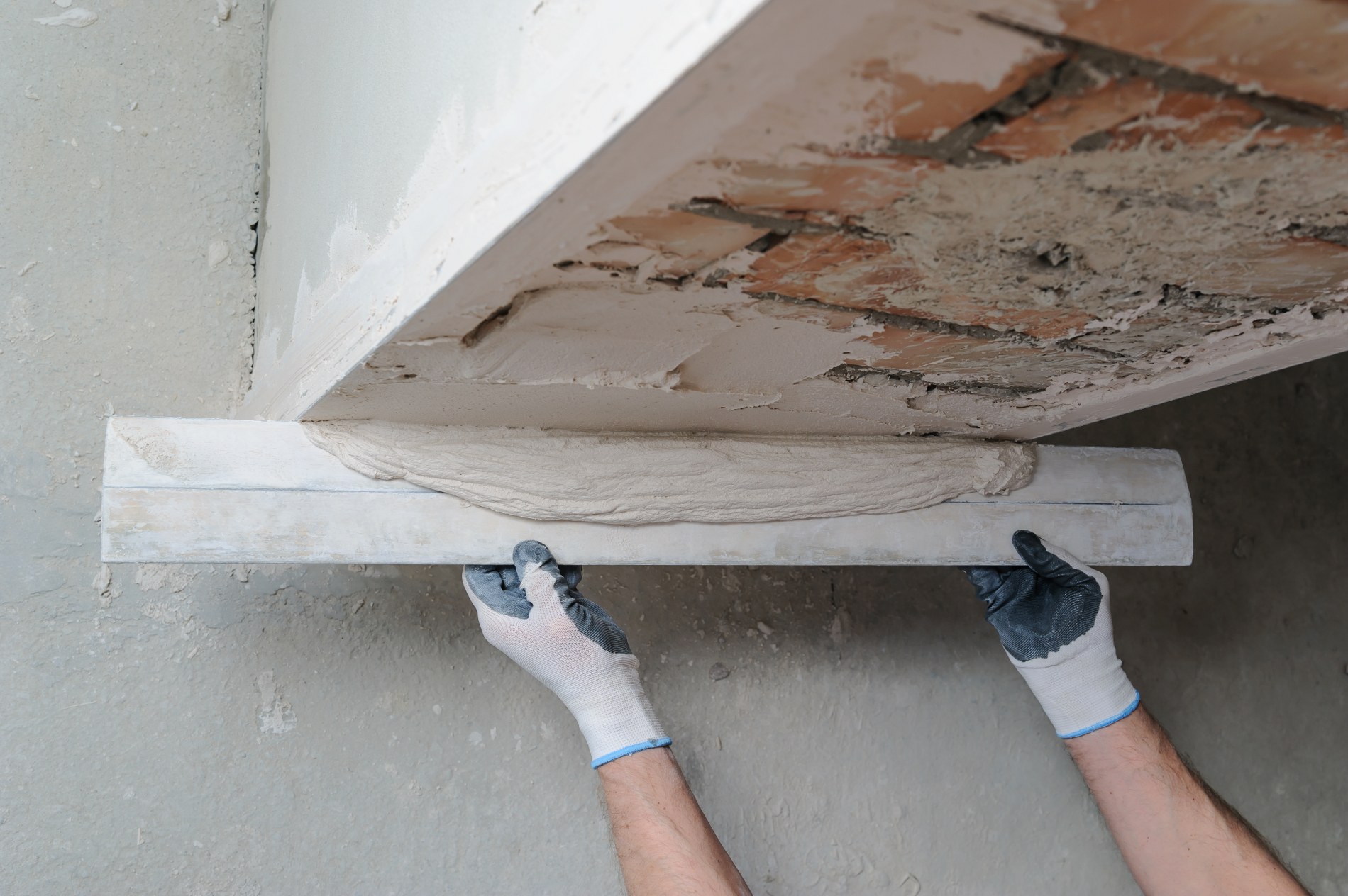 Worker's hands are using a ruler for gypsum plaster. Rénovation maison